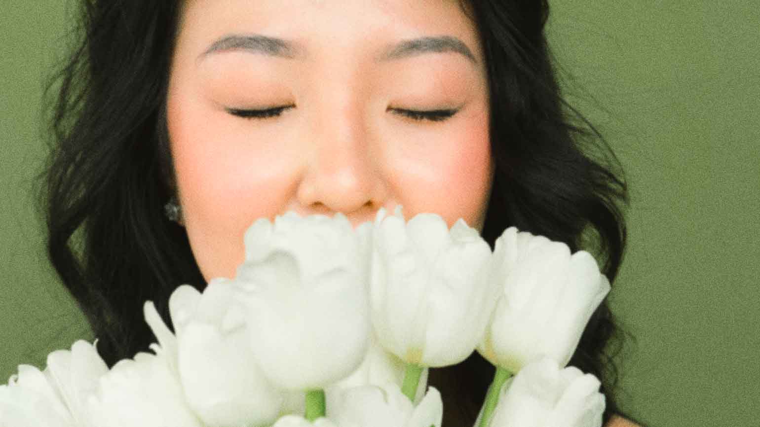 A woman smells white tulips in order to find joy